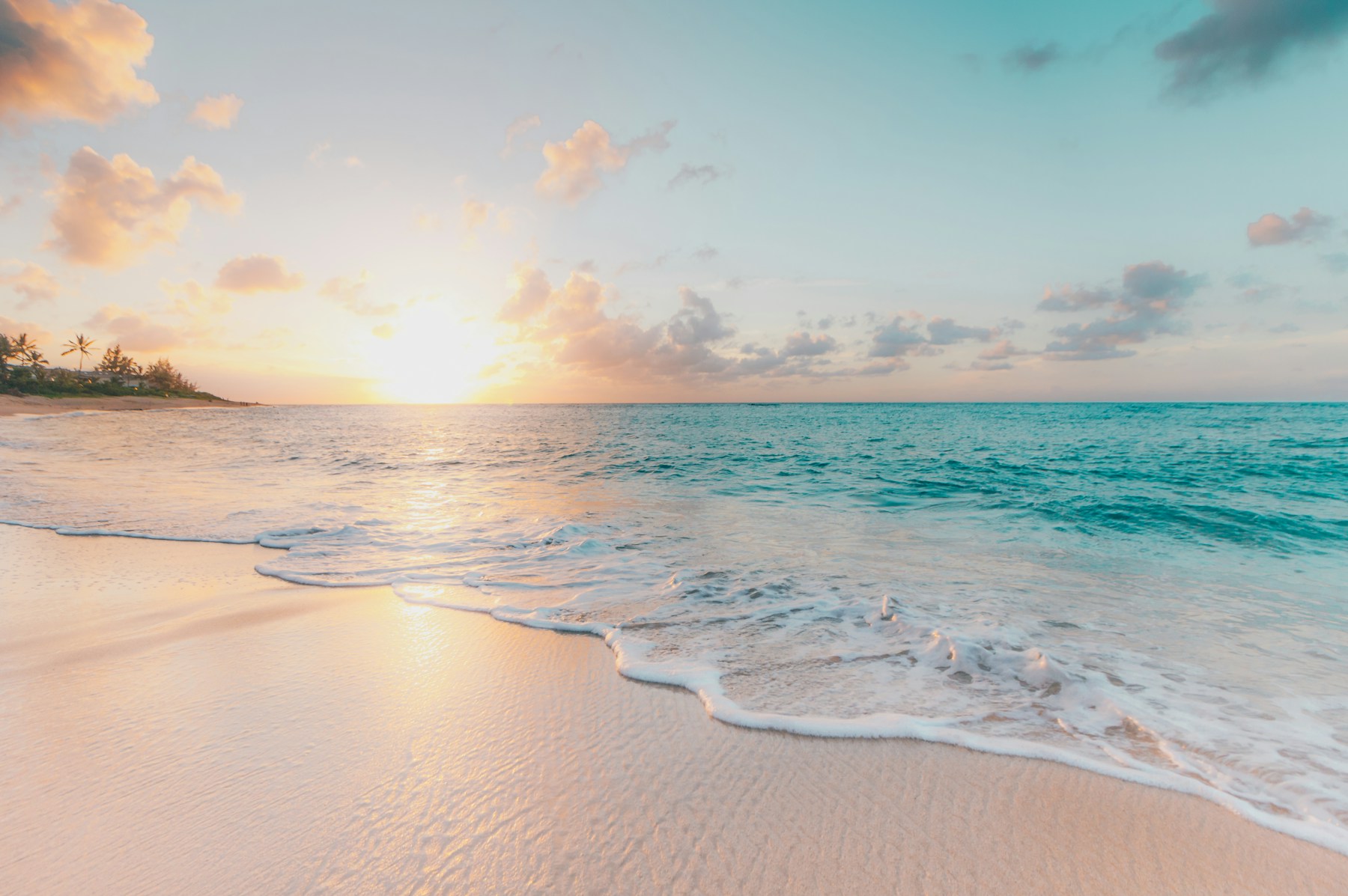 Heller Sandstrand und türkisfarbenes Meer bei Sonnenuntergang