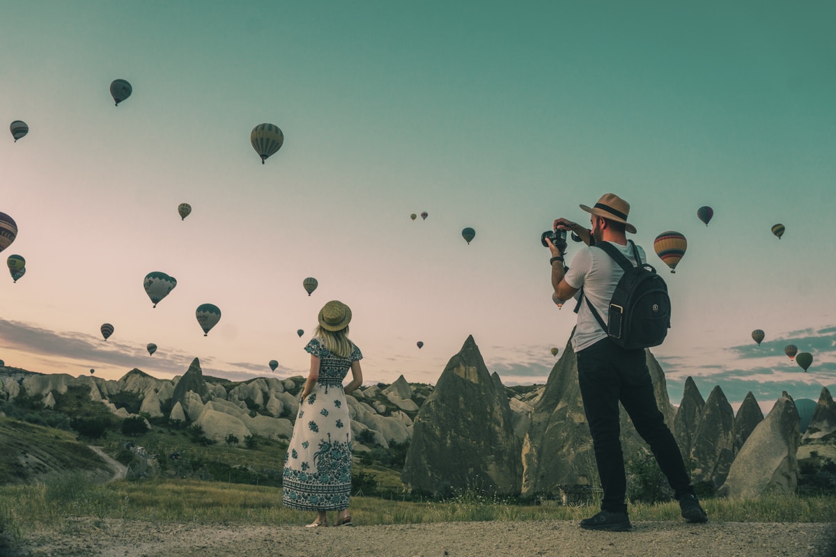 Reisende beobachten Heißluftballons über einer Felslandschaft